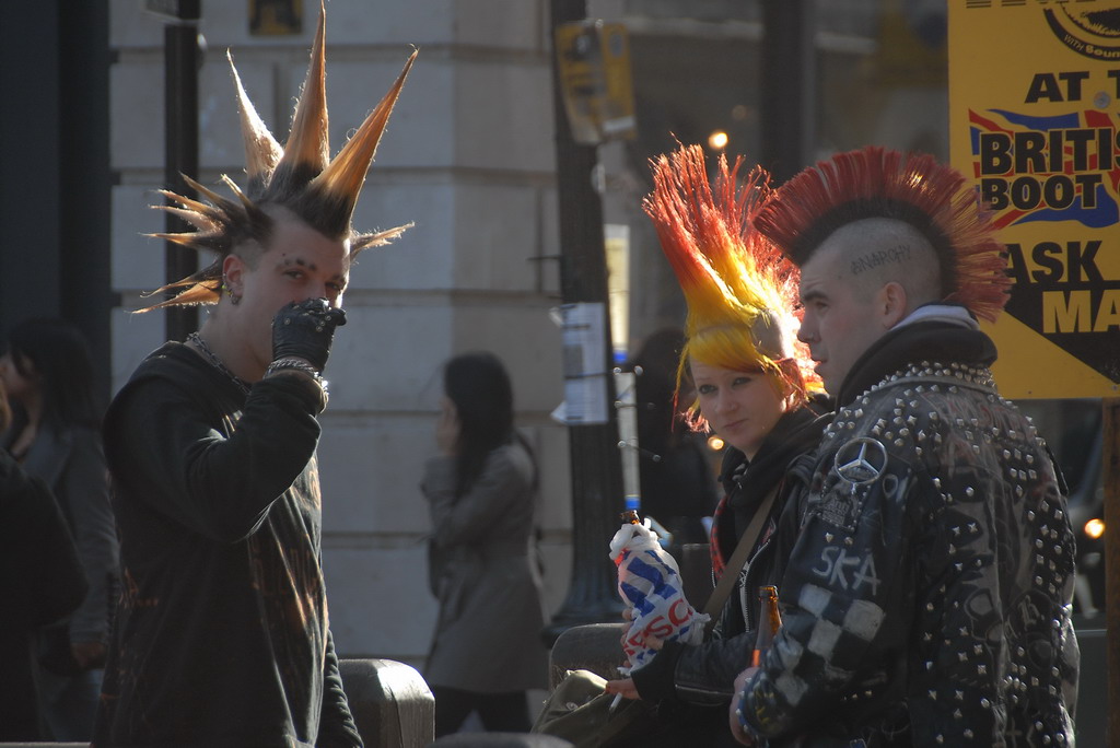 British punks with tall liberty spikes and a red mohawk wearing studded leather jackets covered in patches in Camden, London