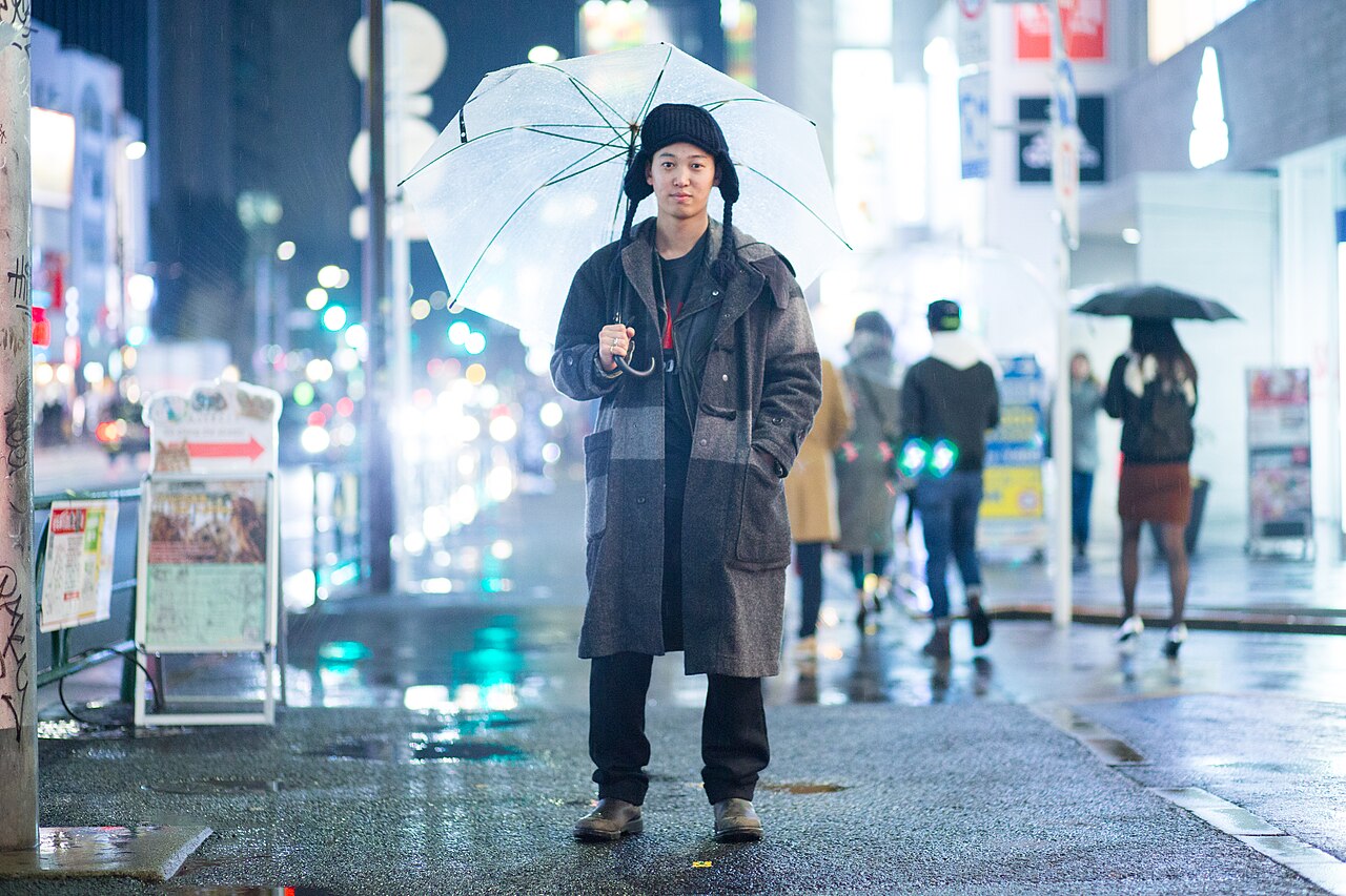 Monochrome layered coat, knit beanie, and boots on a rainy Tokyo street