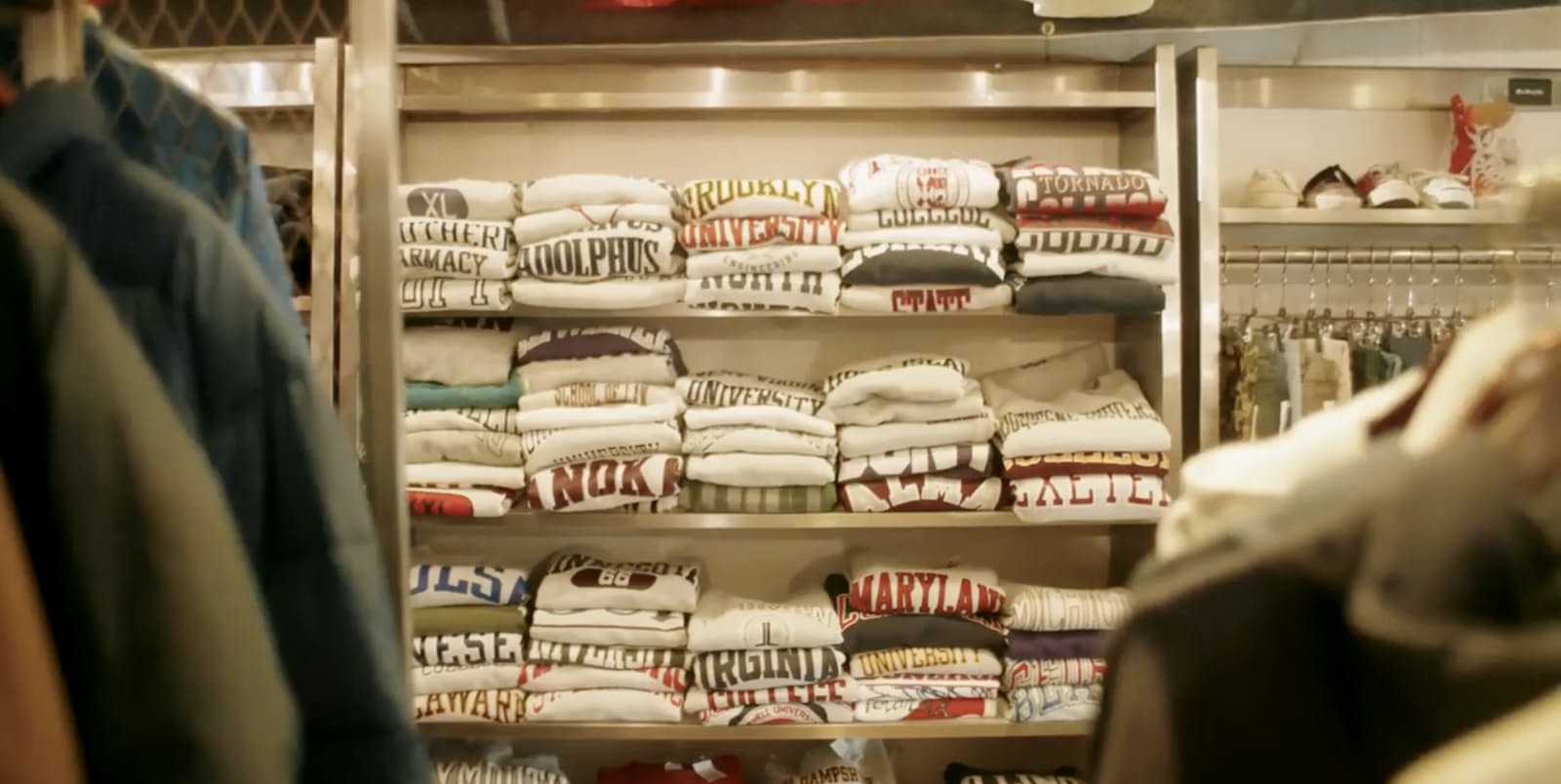 Shelves of folded vintage American university sweatshirts and college print tees