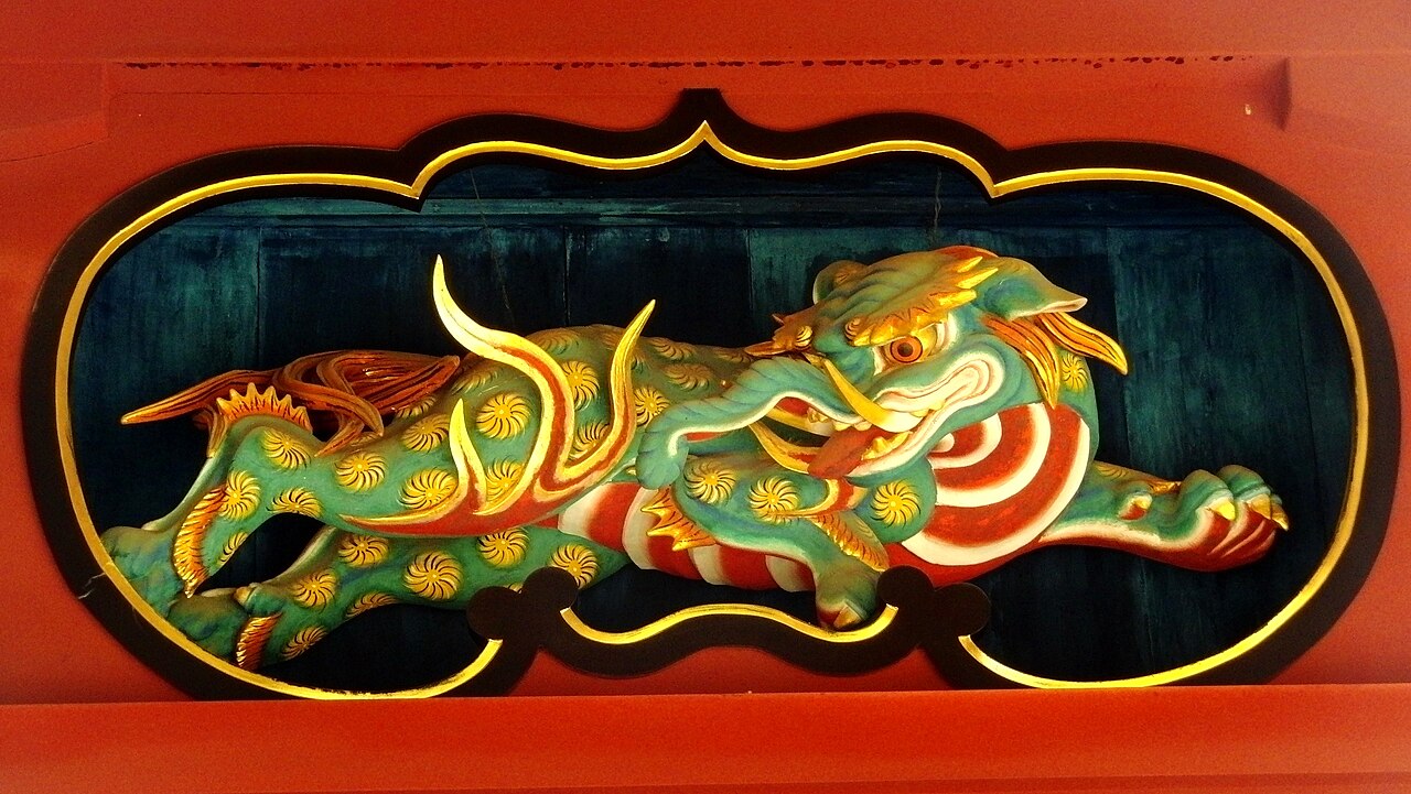 Painted wooden shrine carving of a baku with a striped body, curved horn and clawed paws