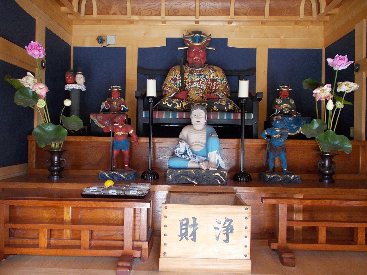 Red faced Enma statue in official robes flanked by smaller demon attendant figures