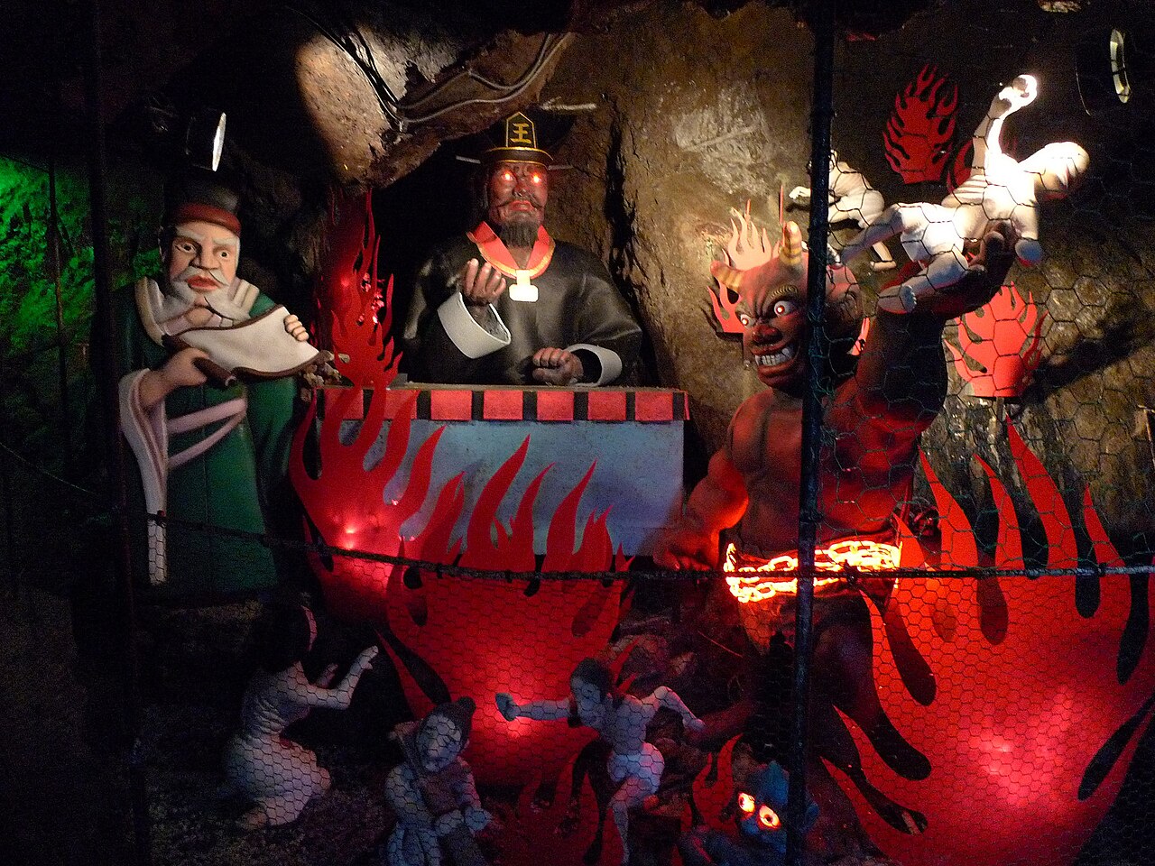 Painted display of Enma judging souls beside an oni dropping figures into a flaming cauldron