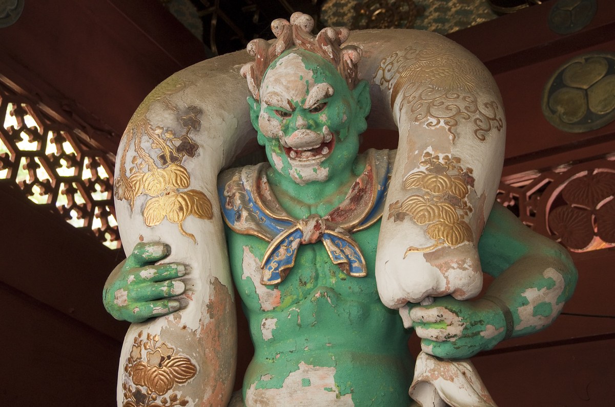 Green-skinned Fujin statue at Taiyuin shrine with a white wind bag draped over both shoulders