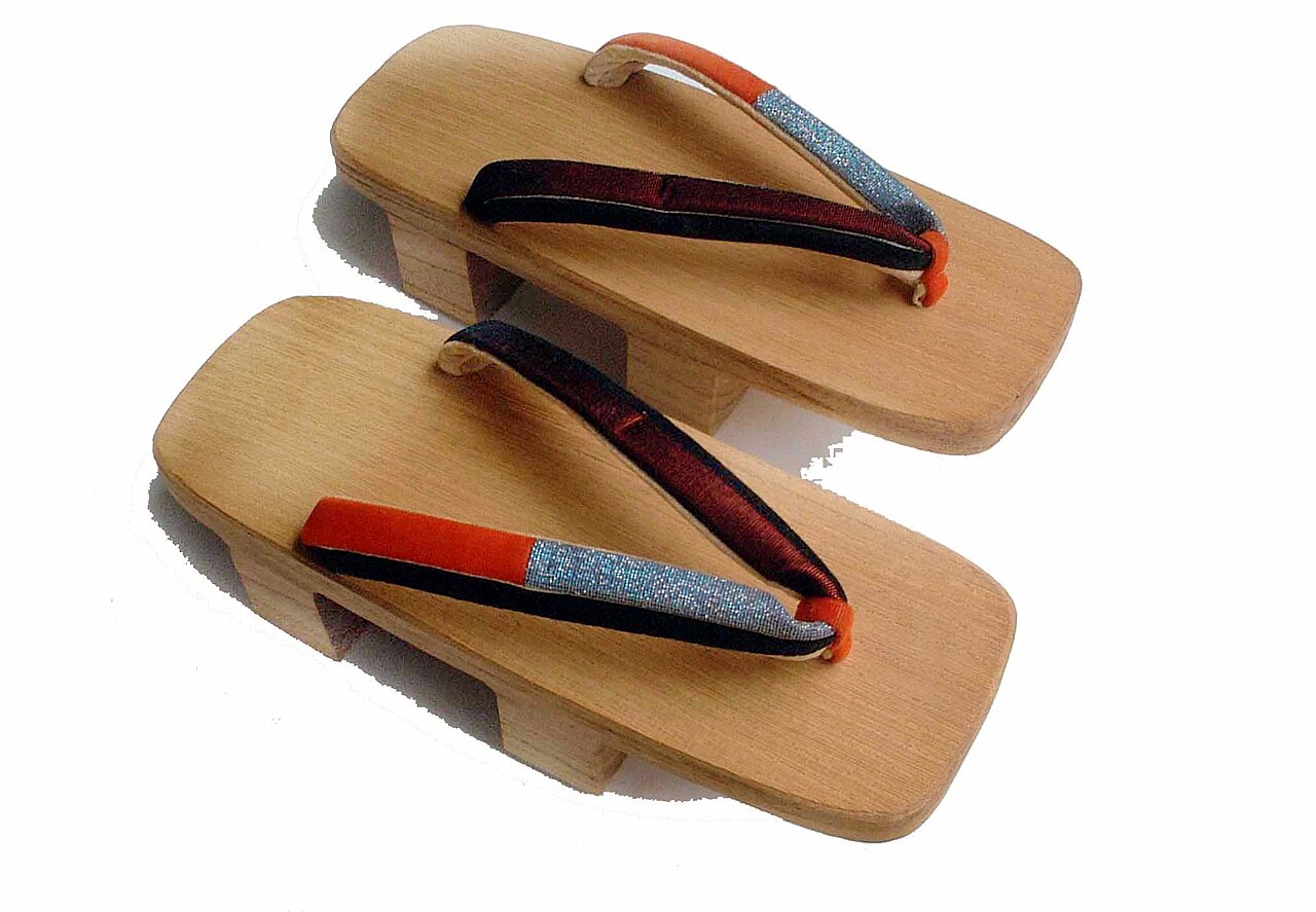 Pair of two toothed wooden geta sandals with orange and silver hanao straps