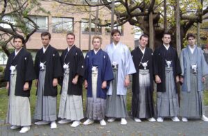 Eight men in black montsuki kimono and striped sendaihira hakama with haori jackets