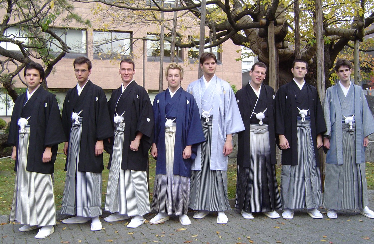 Eight men in black montsuki kimono and striped sendaihira hakama with haori jackets