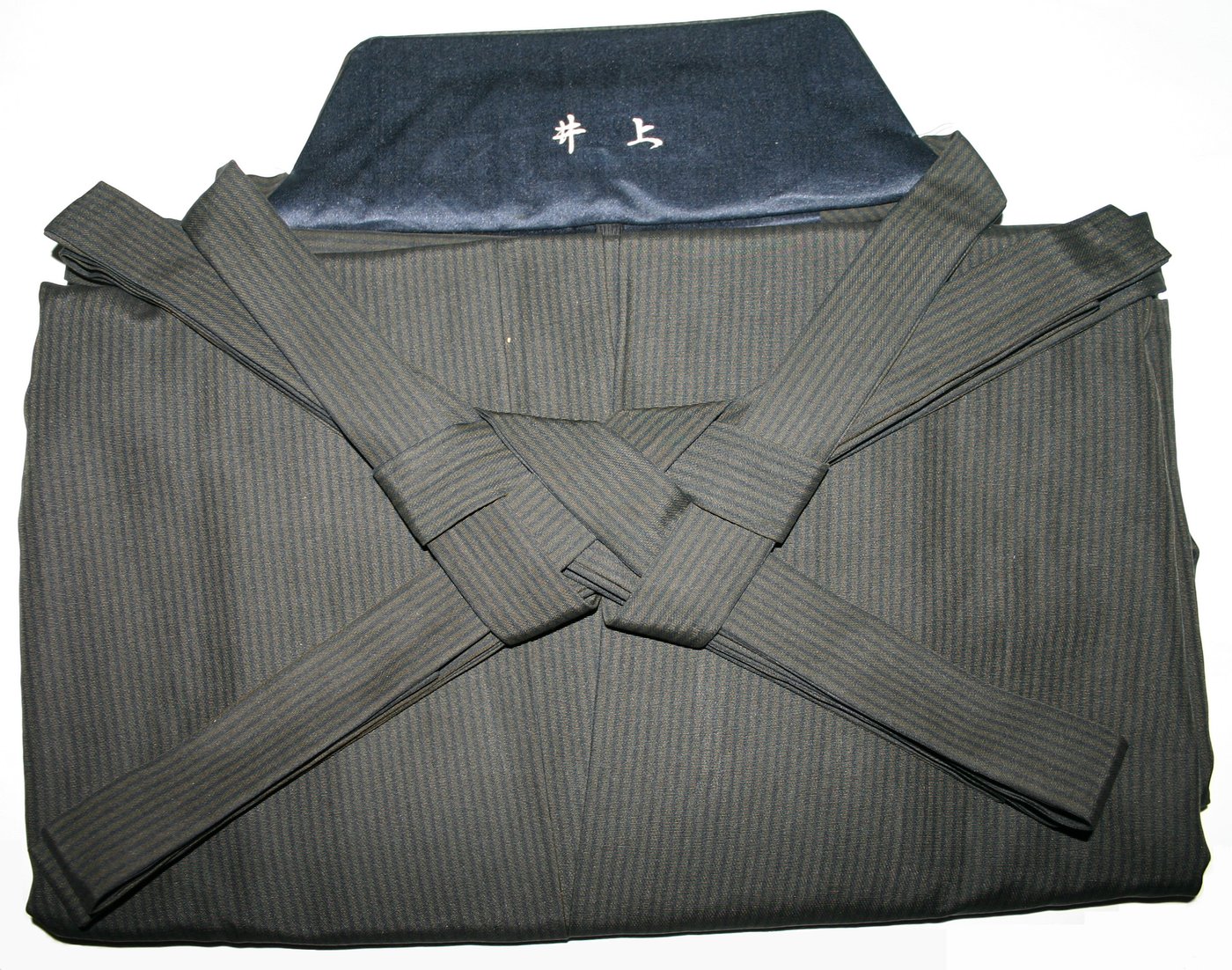 Folded striped hakama with its long himo ties crossed in a flat square knot
