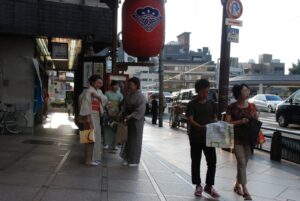 Three women wearing kimono with obi sashes tied, walking on a street in Kyoto, Japan