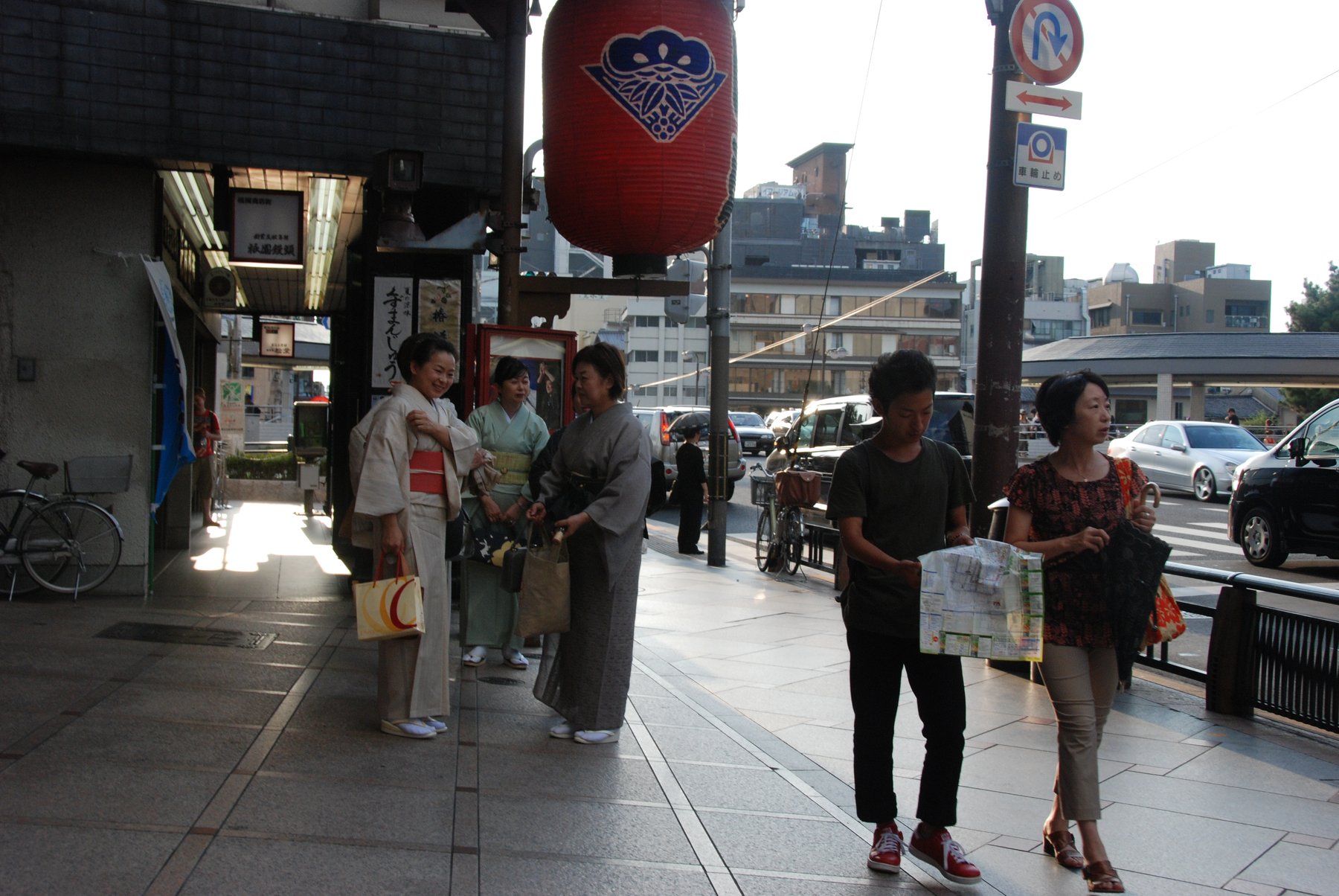 Three women wearing kimono with obi sashes tied, walking on a street in Kyoto, Japan