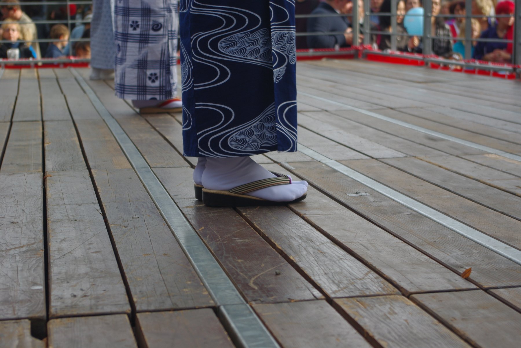 White tabi socks worn in striped zori sandals beneath a navy blue patterned kimono hem