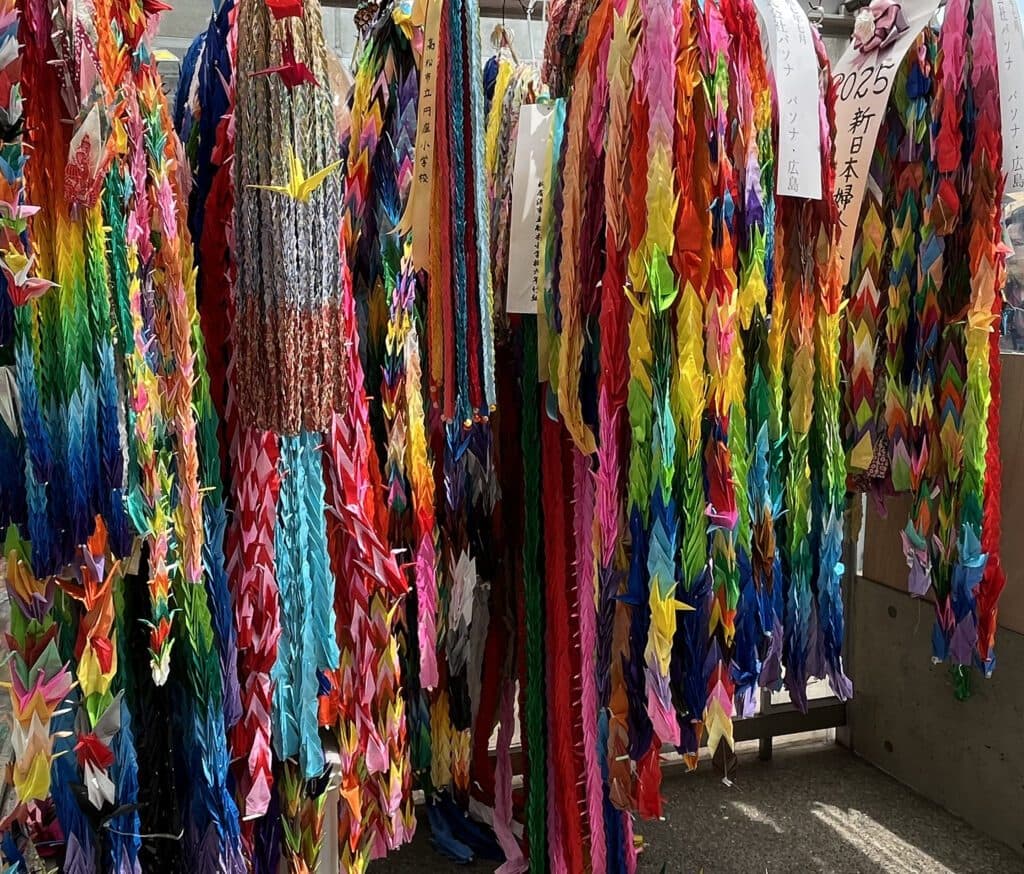 Dense curtains of folded senbazuru paper crane garlands in many colors hung at a peace memorial
