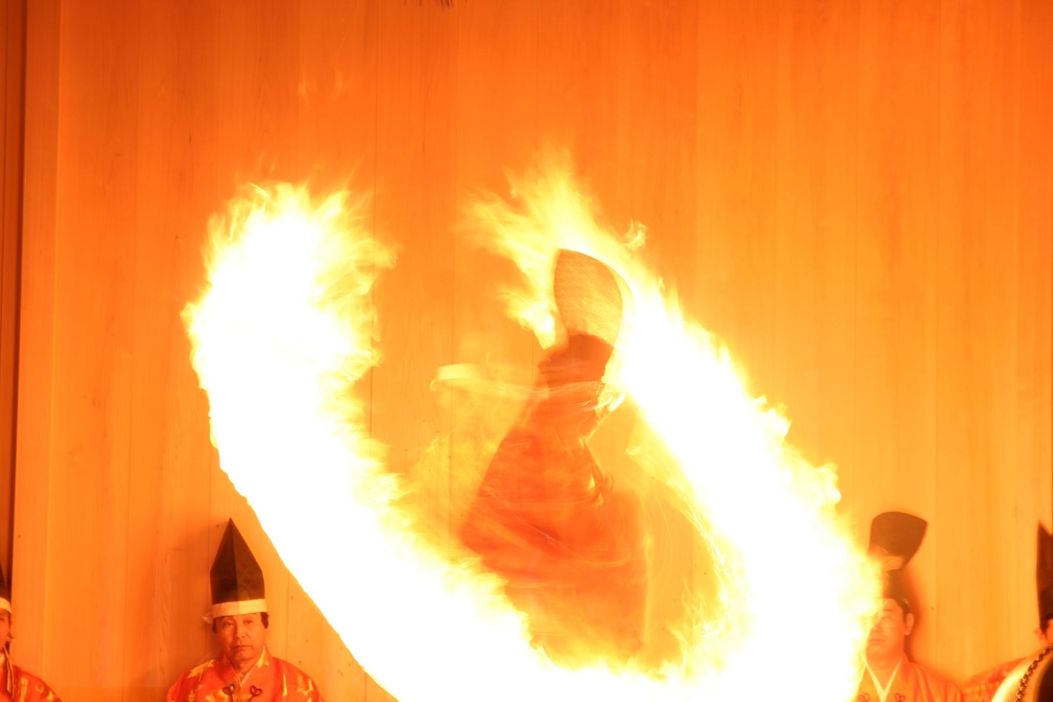 A Shinto priest performing a fire ritual with large flames at a Japanese fire festival