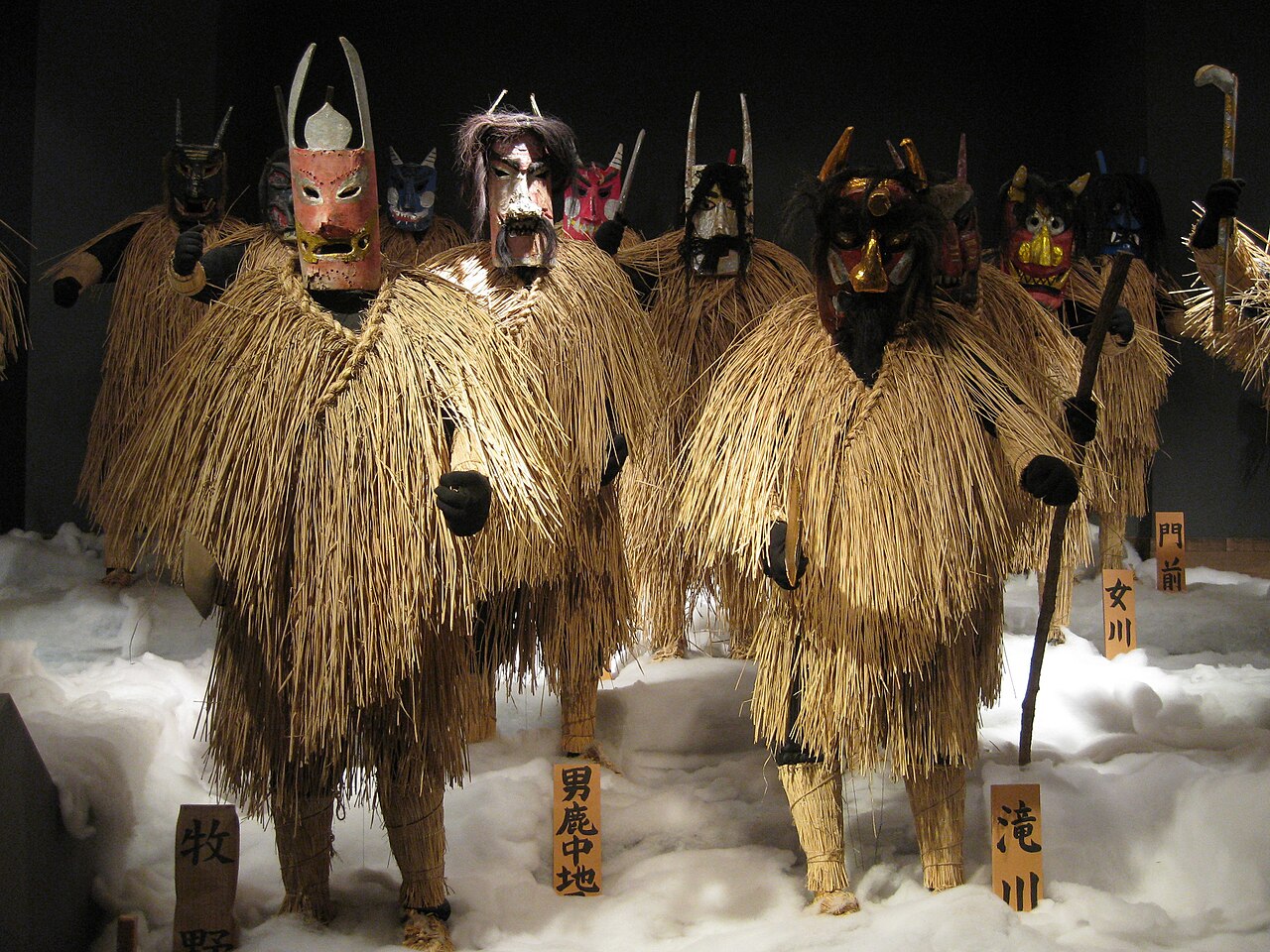 Namahage ogre masks and straw capes displayed on artificial snow in a folklore exhibit