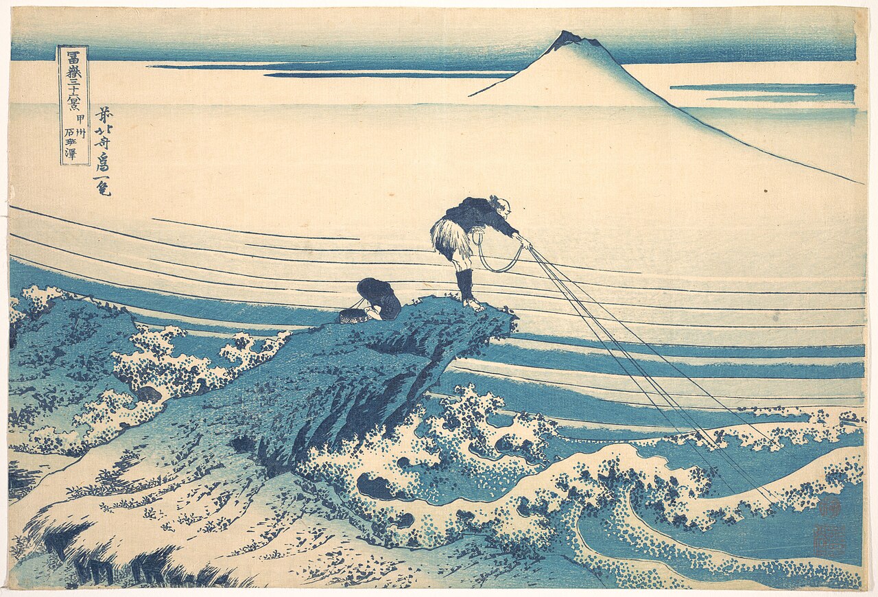 Blue-ink Hokusai print of two fishermen casting lines from a rock into breaking waves with Mount Fuji on the horizon