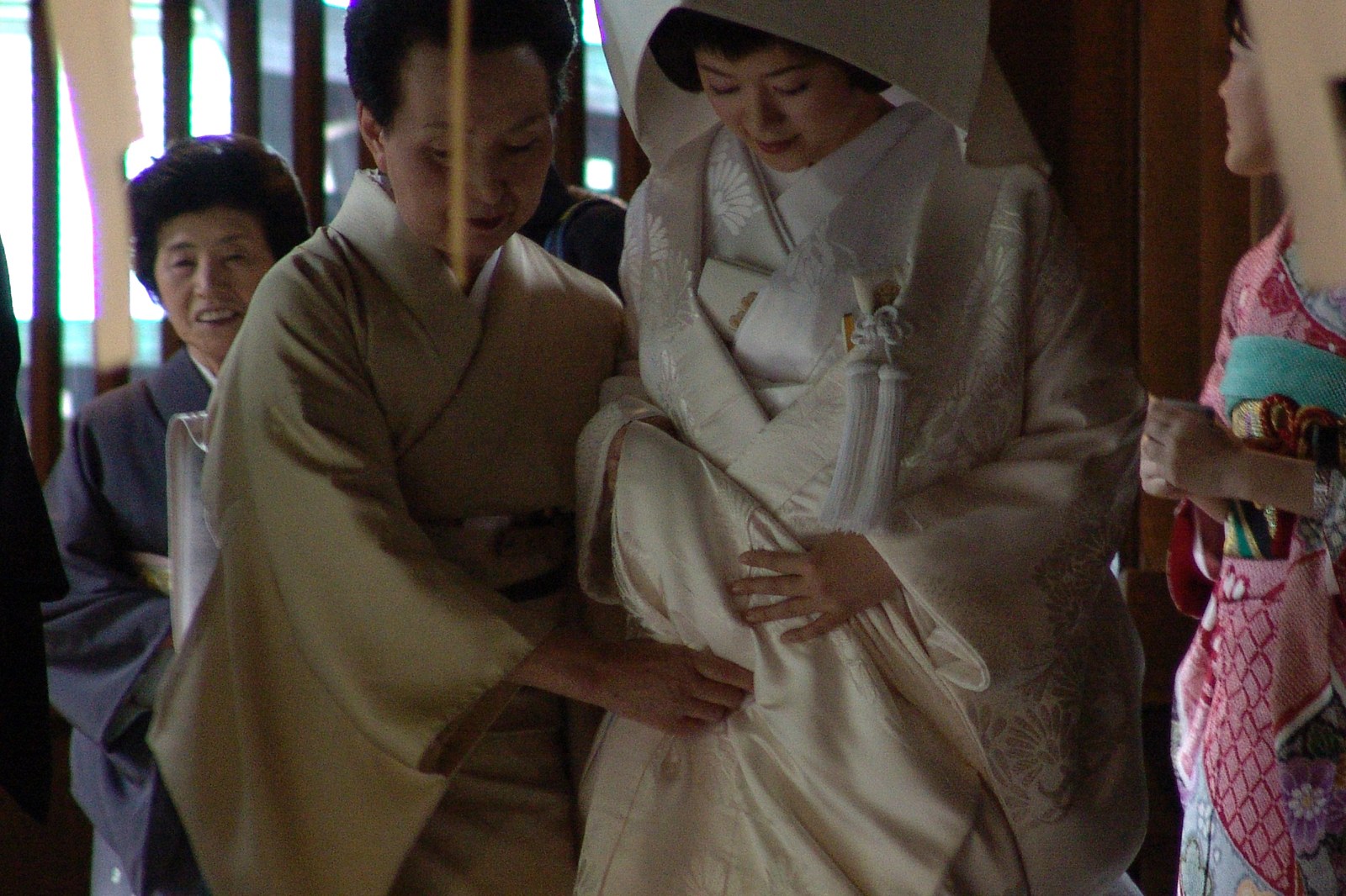 Japanese bride wearing a white shiromuku kimono with gold crane embroidery under a rounded white wataboshi hood