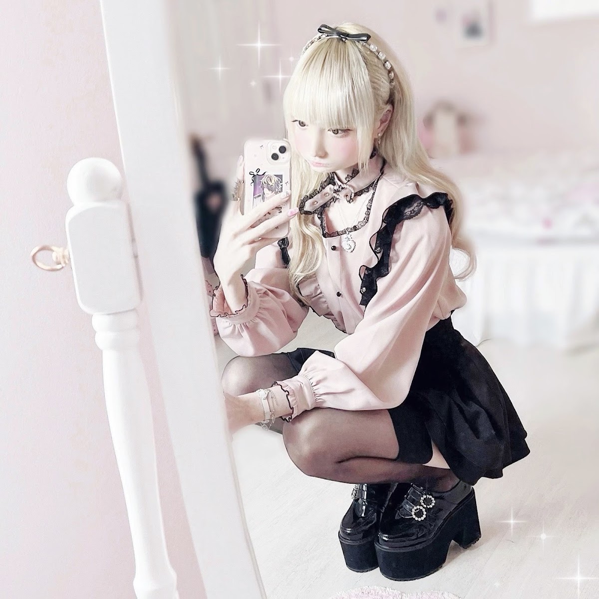 A jirai kei coordinate with pale makeup, a black satin hair bow, black lace collar and chunky platform Mary Janes