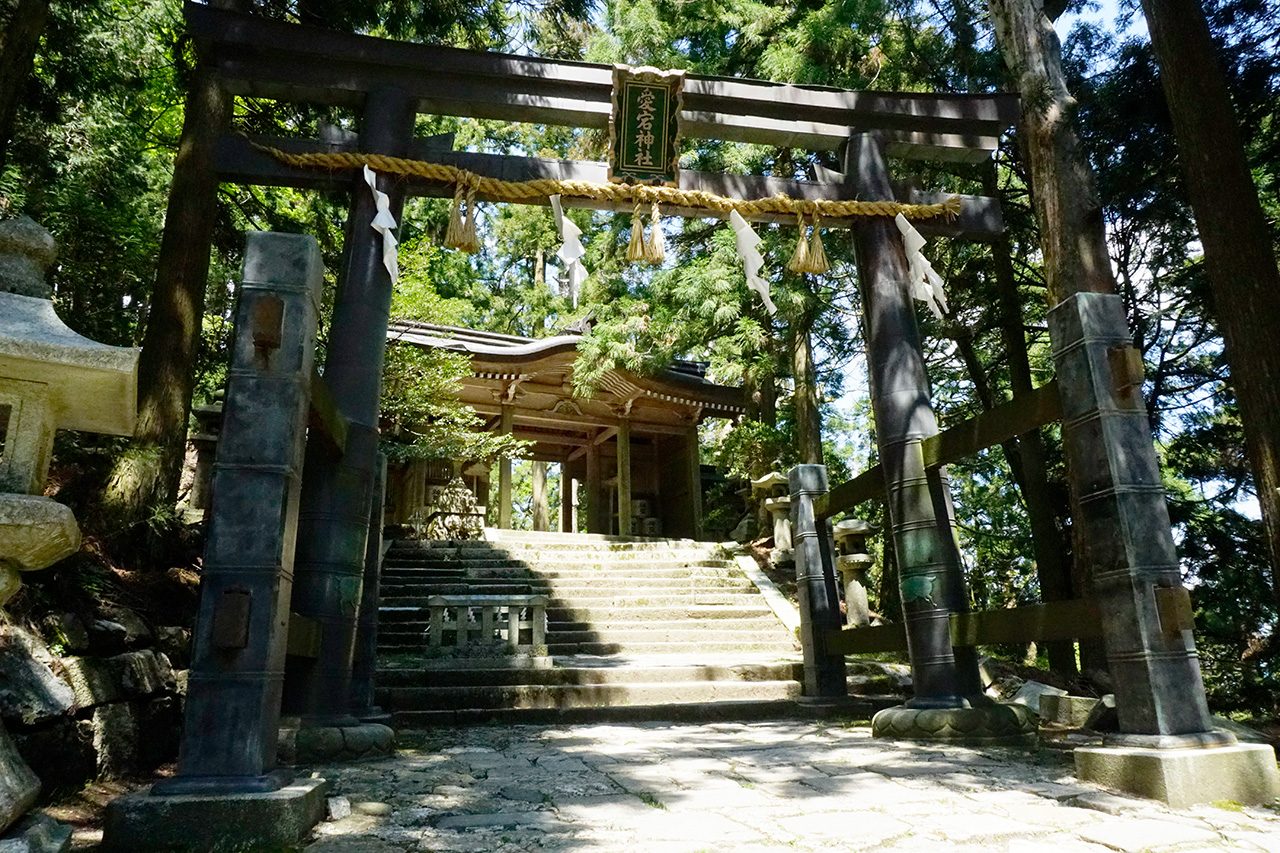 Weathered torii gate hung with a straw shimenawa rope leading to the wooden hall of Atago Shrine on Mount Atago in Kyoto