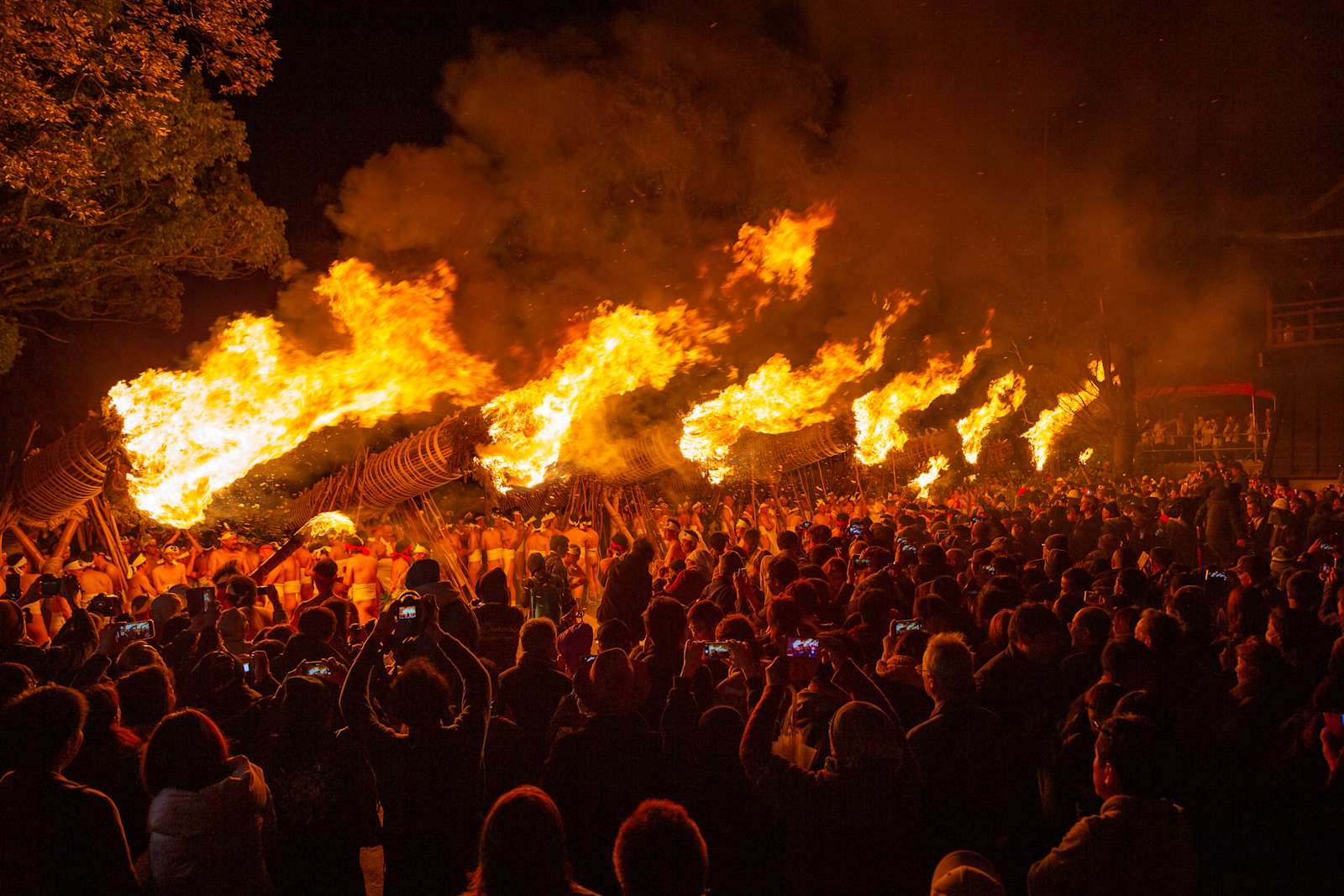 Enormous burning torches raised at night before a crowd at the Oniyo fire festival in Japan