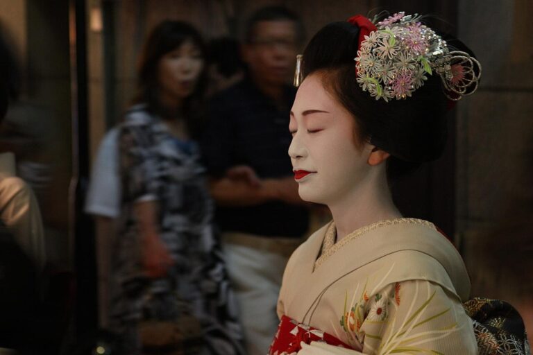 Maiko in a pale kimono wearing a silver and pink flower kanzashi in her hair