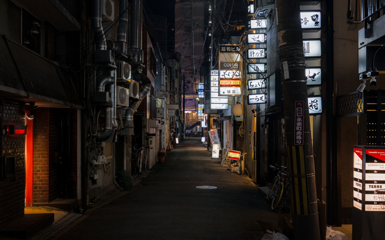Dark narrow alley in a Japanese nightlife district lined with illuminated bar and restaurant signboards