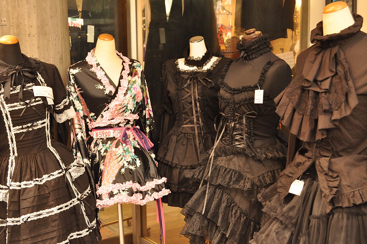 Black Gothic Lolita dresses with lace trim, ruffled skirts and corset lacing displayed on mannequins in a Japanese shop window