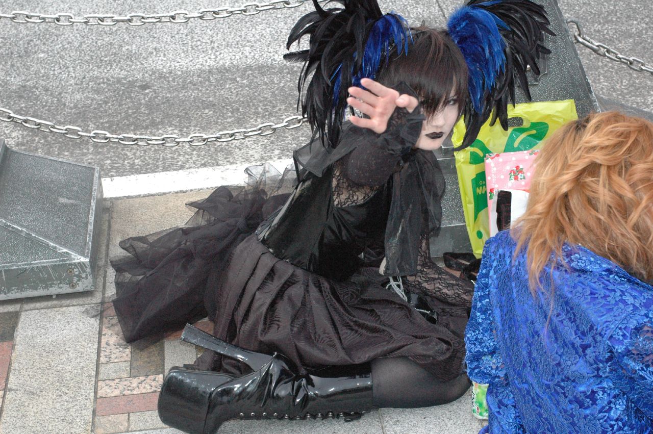 Dark Harajuku street look with an all-black lace outfit, blue and black feather hair pieces and studded platform boots