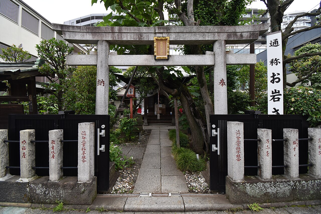 Stone torii gate and small shrine building at Oiwa Inari Tamiya Shrine in Yotsuya, Tokyo