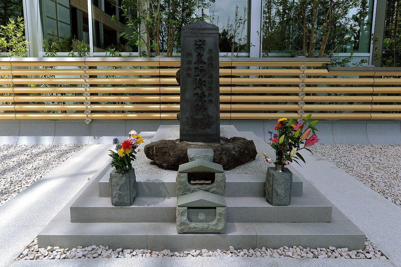 Stone monument at the Taira no Masakado head mound in Tokyo with fresh flower offerings