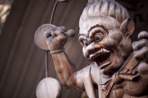 Carved wooden Raijin statue baring fangs, raising a mallet inside his ring of drums