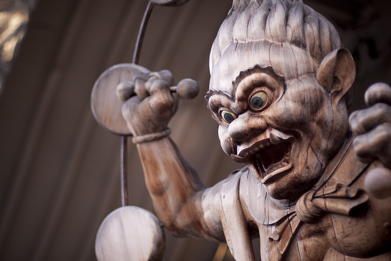 Carved wooden Raijin statue baring fangs, raising a mallet inside his ring of drums