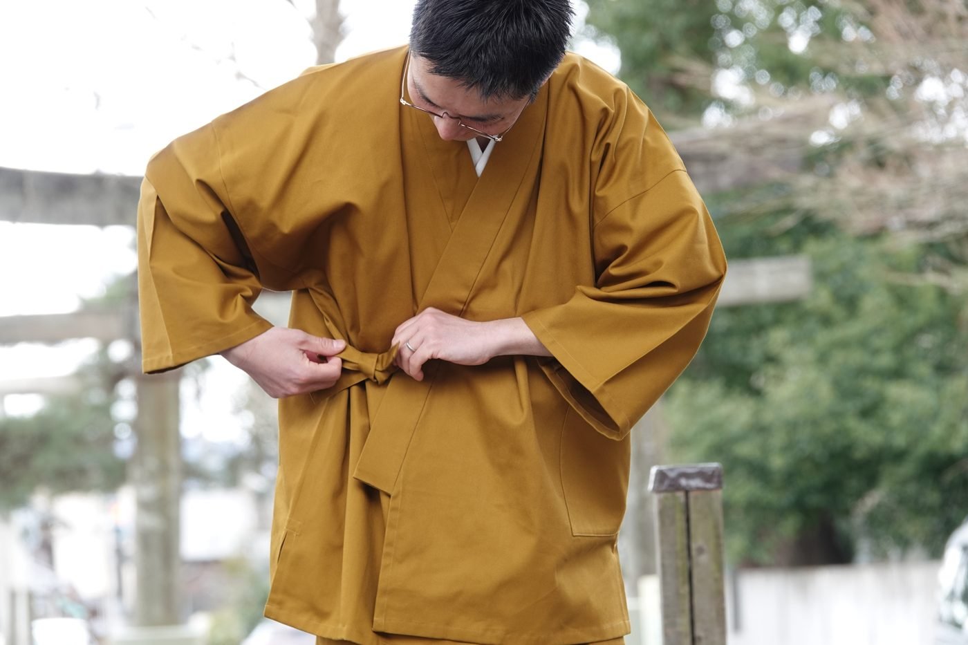 Man tying the side waist tie of a mustard yellow samue jacket