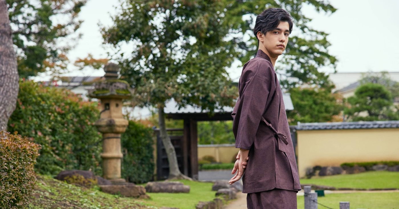 Man wearing a brown samue jacket and matching trousers in a Japanese garden