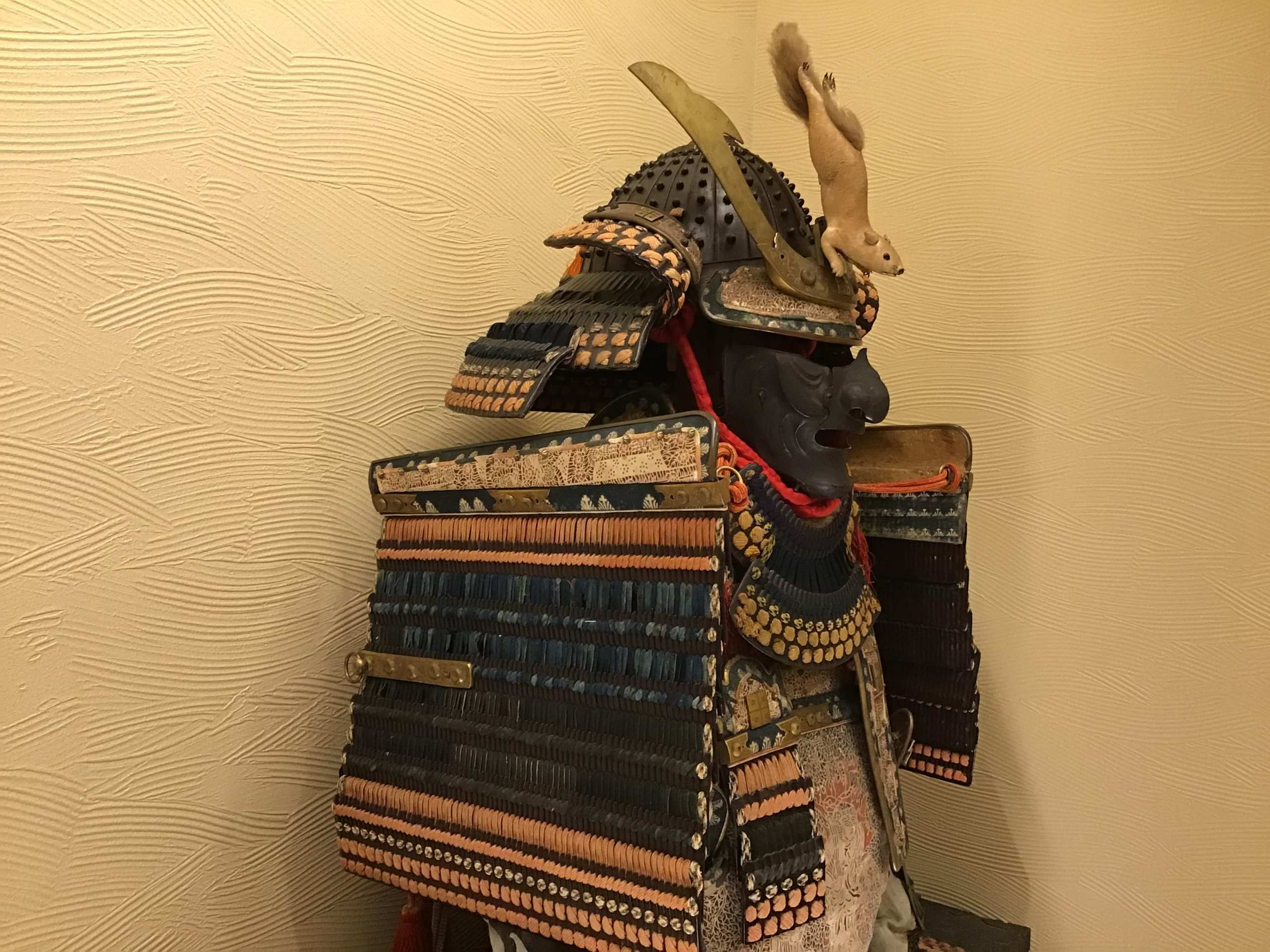 Side angle of a samurai o-yoroi armor set showing the boxy kusazuri skirt panels and large sode shoulder guards