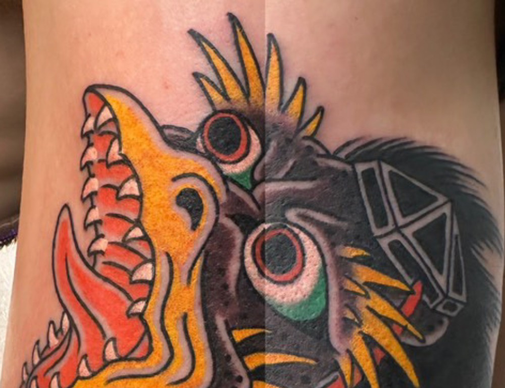 Color tattoo showing a split tengu design, a yellow beaked karasu tengu on one side and a dark crow-like head on the other