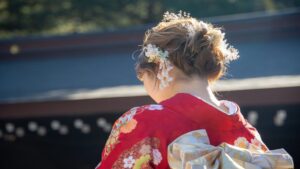 Young woman in a red floral furisode kimono with a patterned obi at a shrine