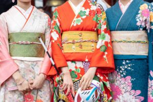 Three women wearing patterned kimono with wide obi sashes tied at the waist