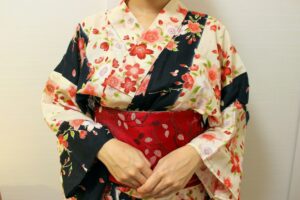 Close-up of a floral yukata wrapped left over right and closed with a red obi
