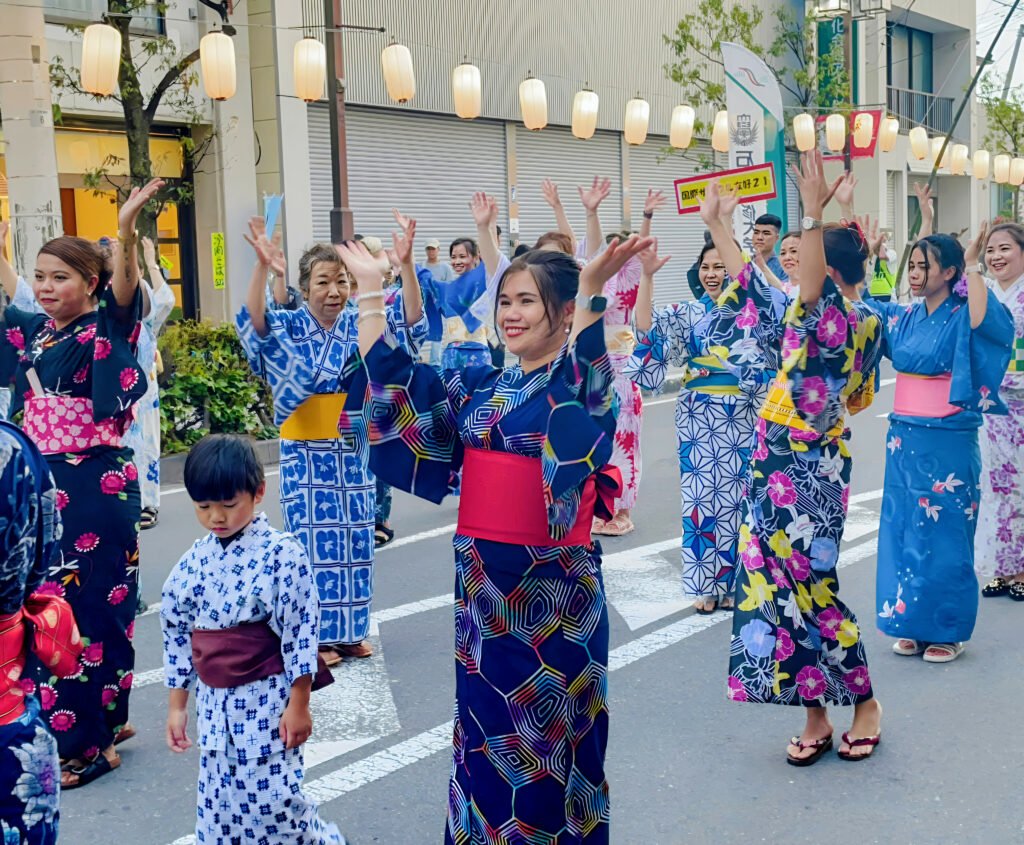 Crowd of people in patterned yukata dancing at a Japanese summer street festival