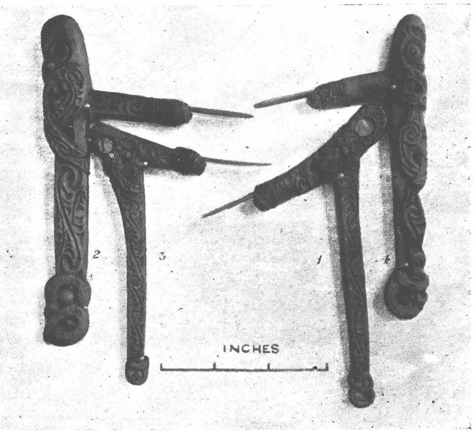 Photograph of four carved wooden tattooing tools with bone blades beside an inches scale bar